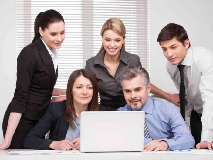 Large group of people looking together at laptop