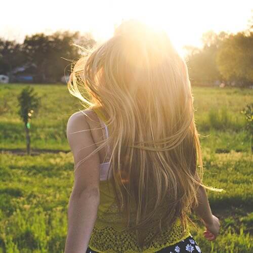 girl with long blonde hair running in the field