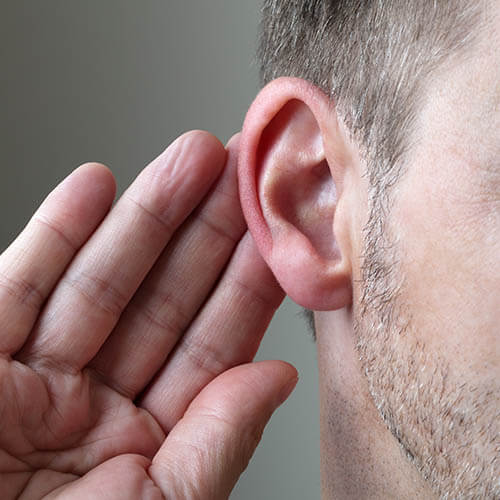 male putting hand behind ear to hear better