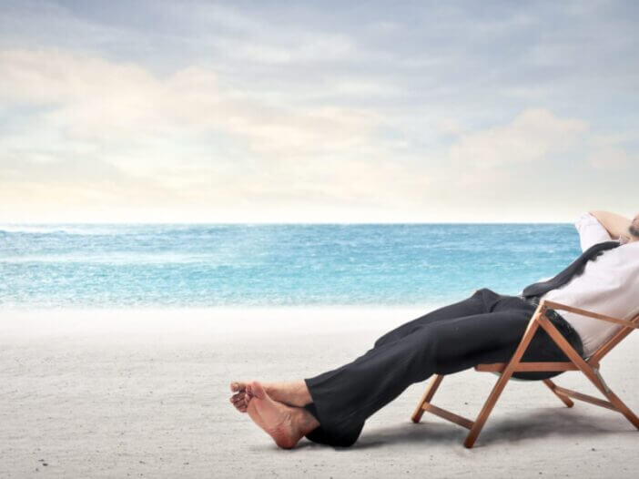 man in suit on a wood chair on the beach