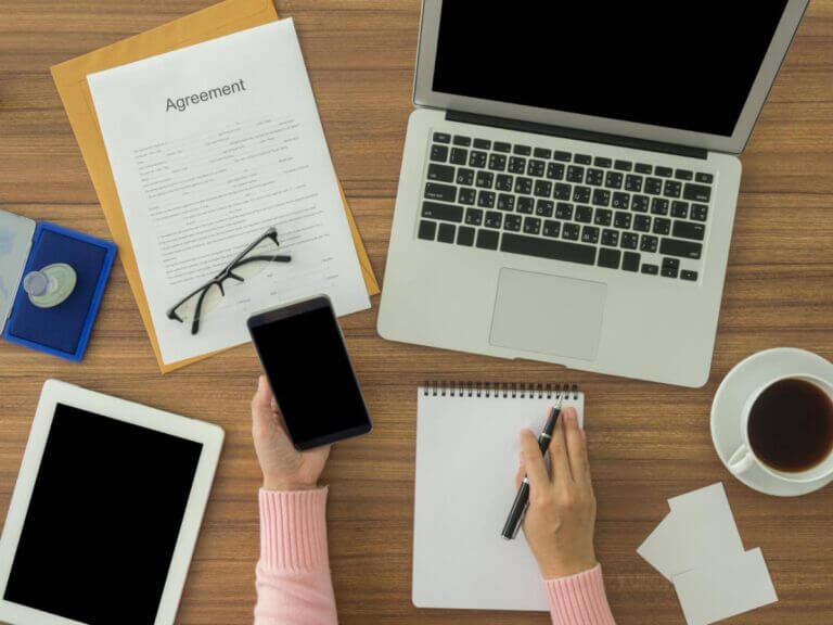 women with electronic devices reviewing an agreement