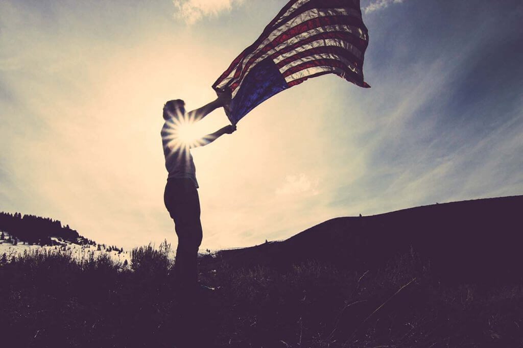 person holding American flag as it blows in the wind