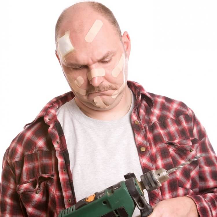 man with bandaids all over face looking confused at nail gun