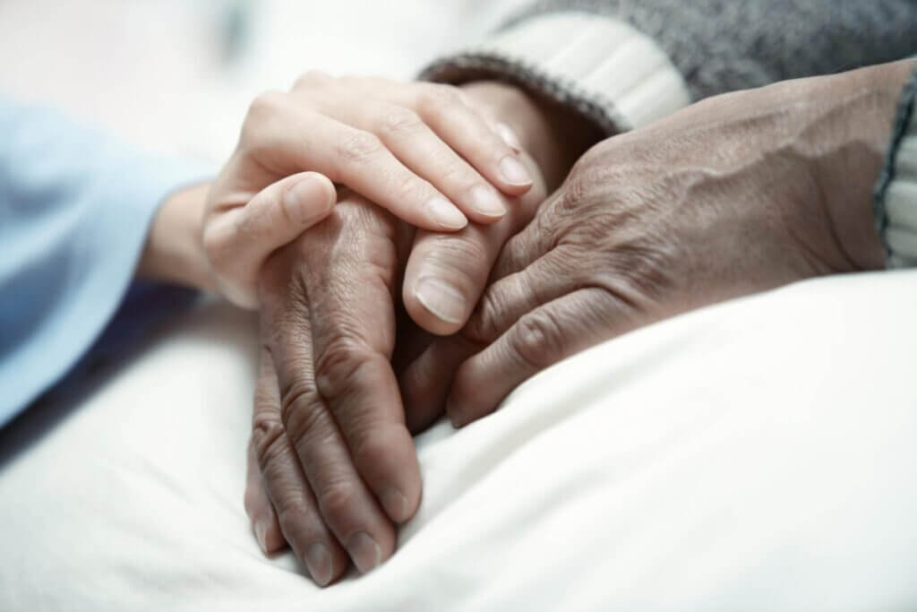 young and old hands holding each other in a hospital bed