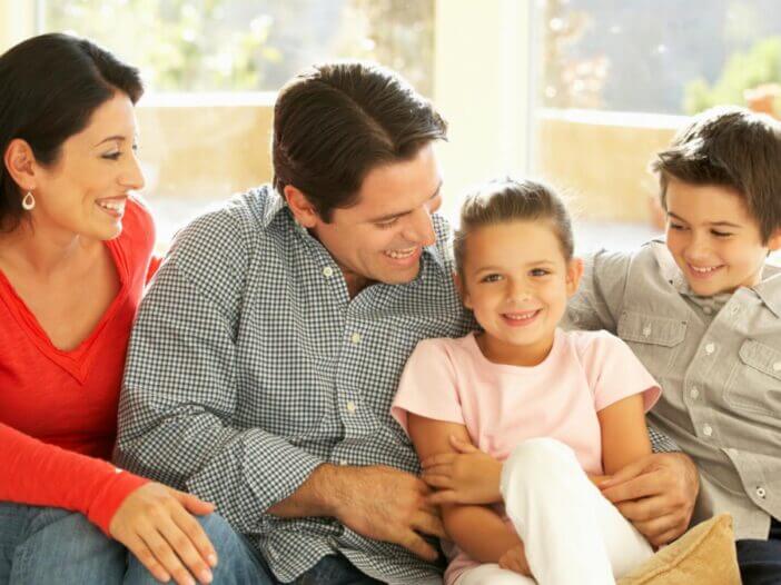 family sitting on couch smiling and holding eachother