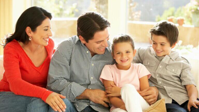 family sitting on couch smiling and holding eachother