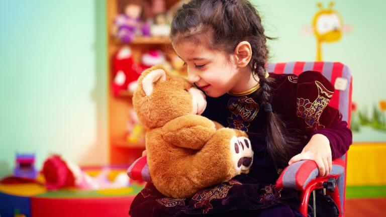 little girl in wheel chair with teddy bear