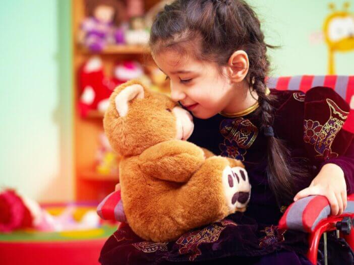 little girl in wheel chair with teddy bear