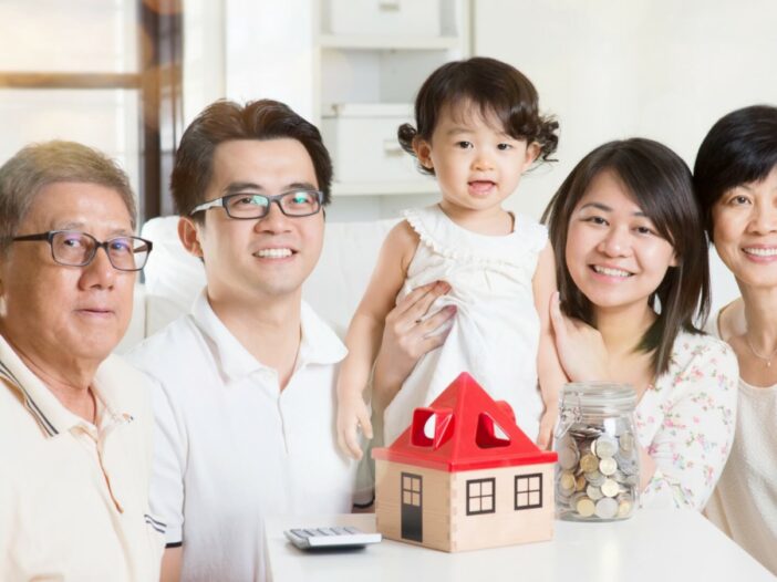 multigenerational family smiling with small house and coins on table