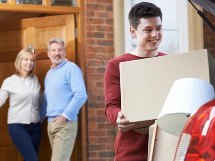 Son packing car up to move with parents in the background