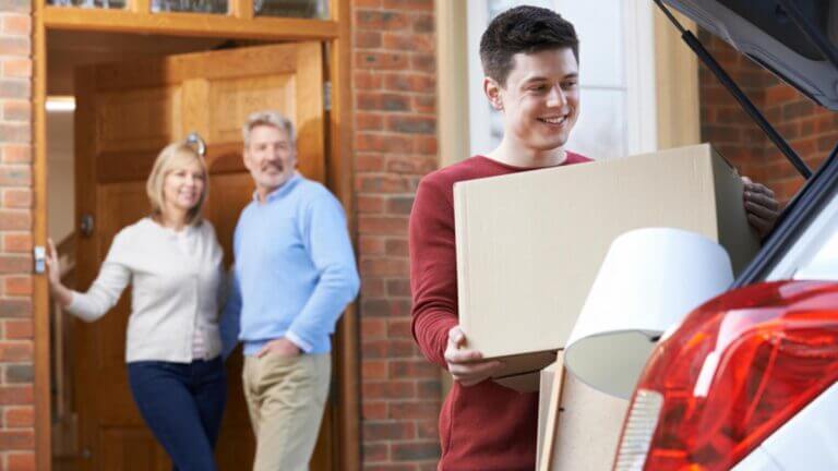 Son packing car up to move with parents in the background