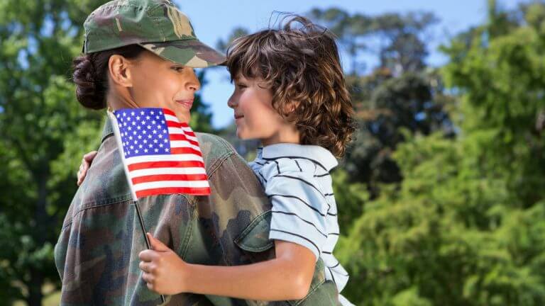 Women Veteran holding son in arms with American Flag