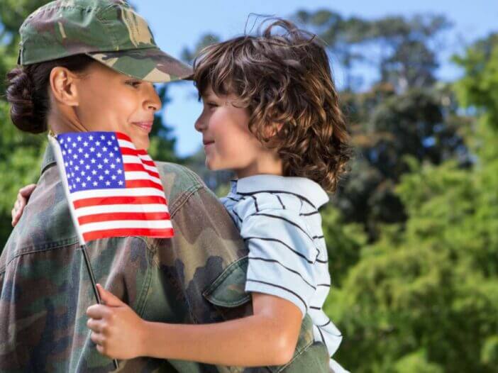 Women Veteran holding son in arms with American Flag