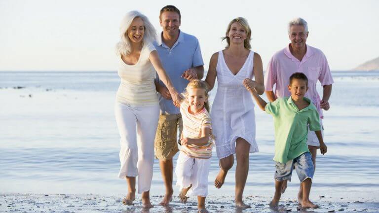 3 generations of family on the beach together running toward camera