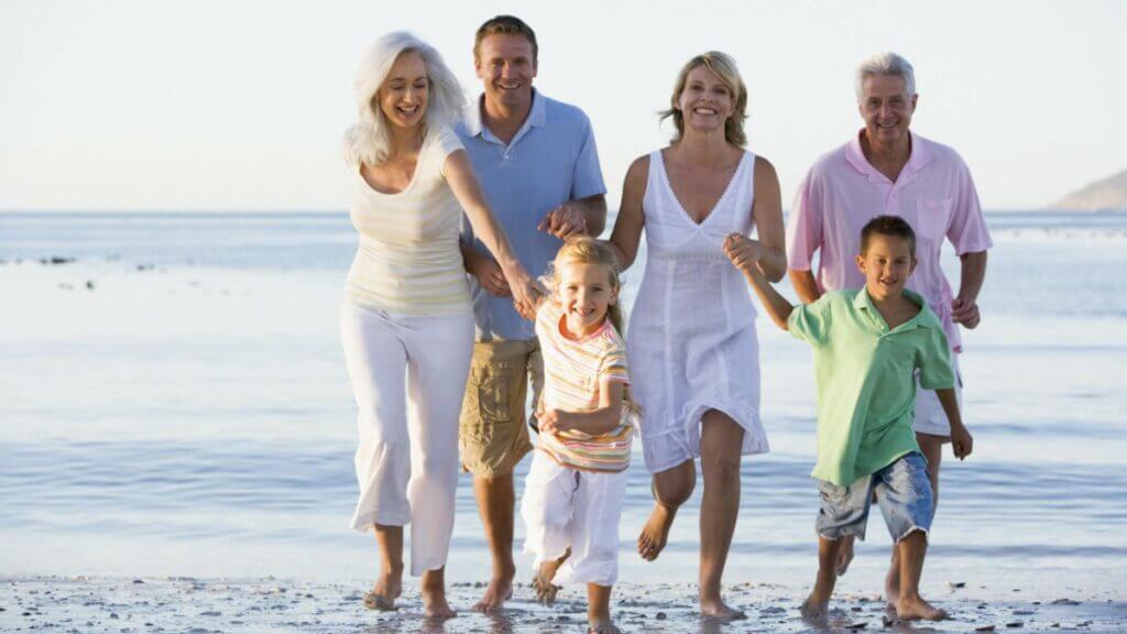 3 generations of family on the beach together running toward camera