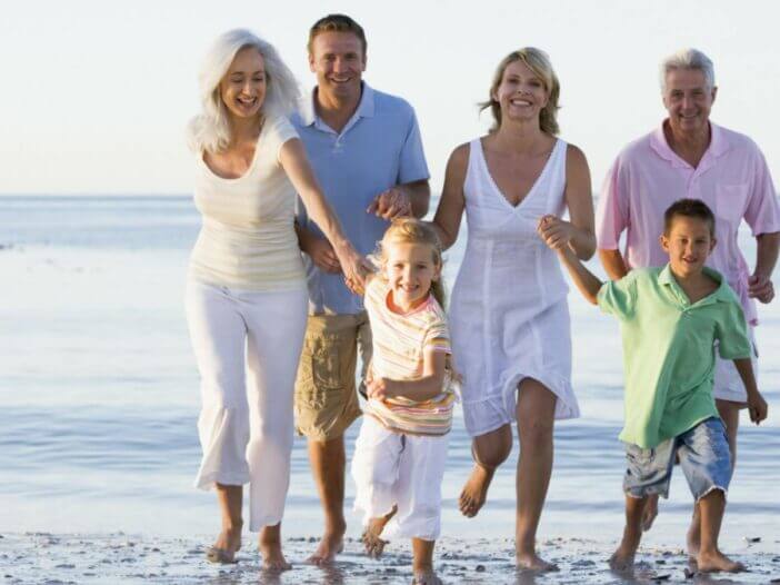 3 generations of family on the beach together running toward camera