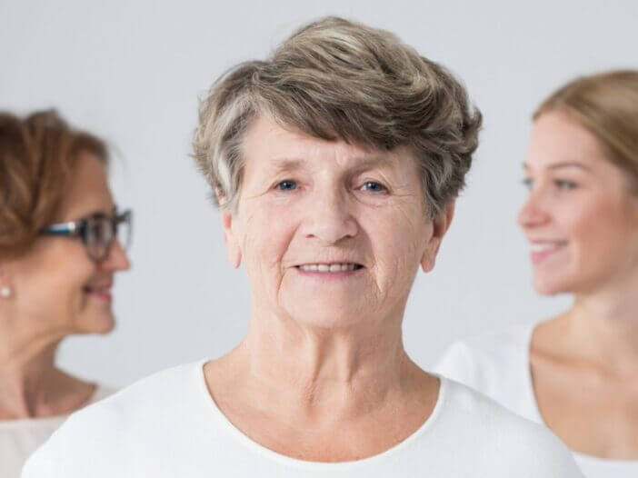 Elder woman with daughter and grand daughter out of focus in the background