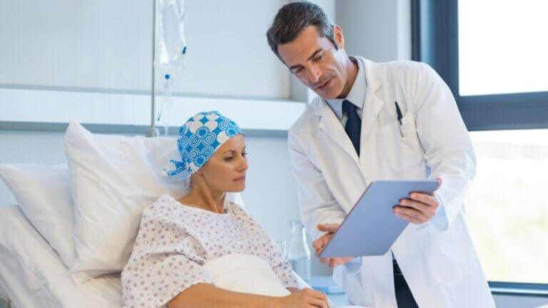 doctor explains something in chart to a patient in hospital bed