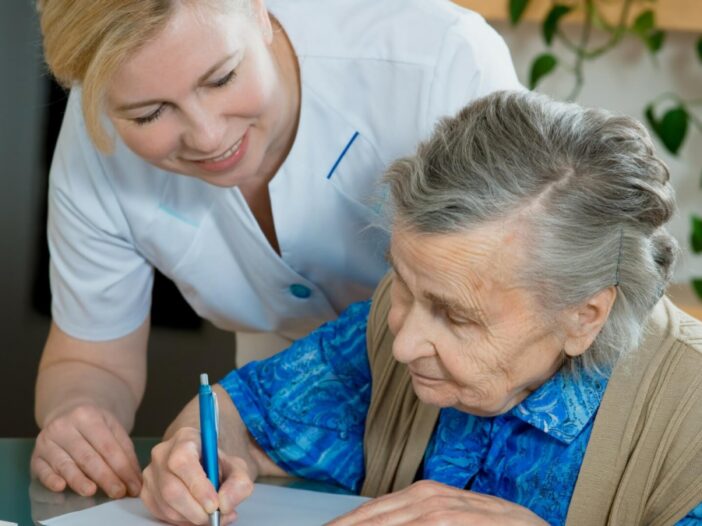 older women signing paper with nurse