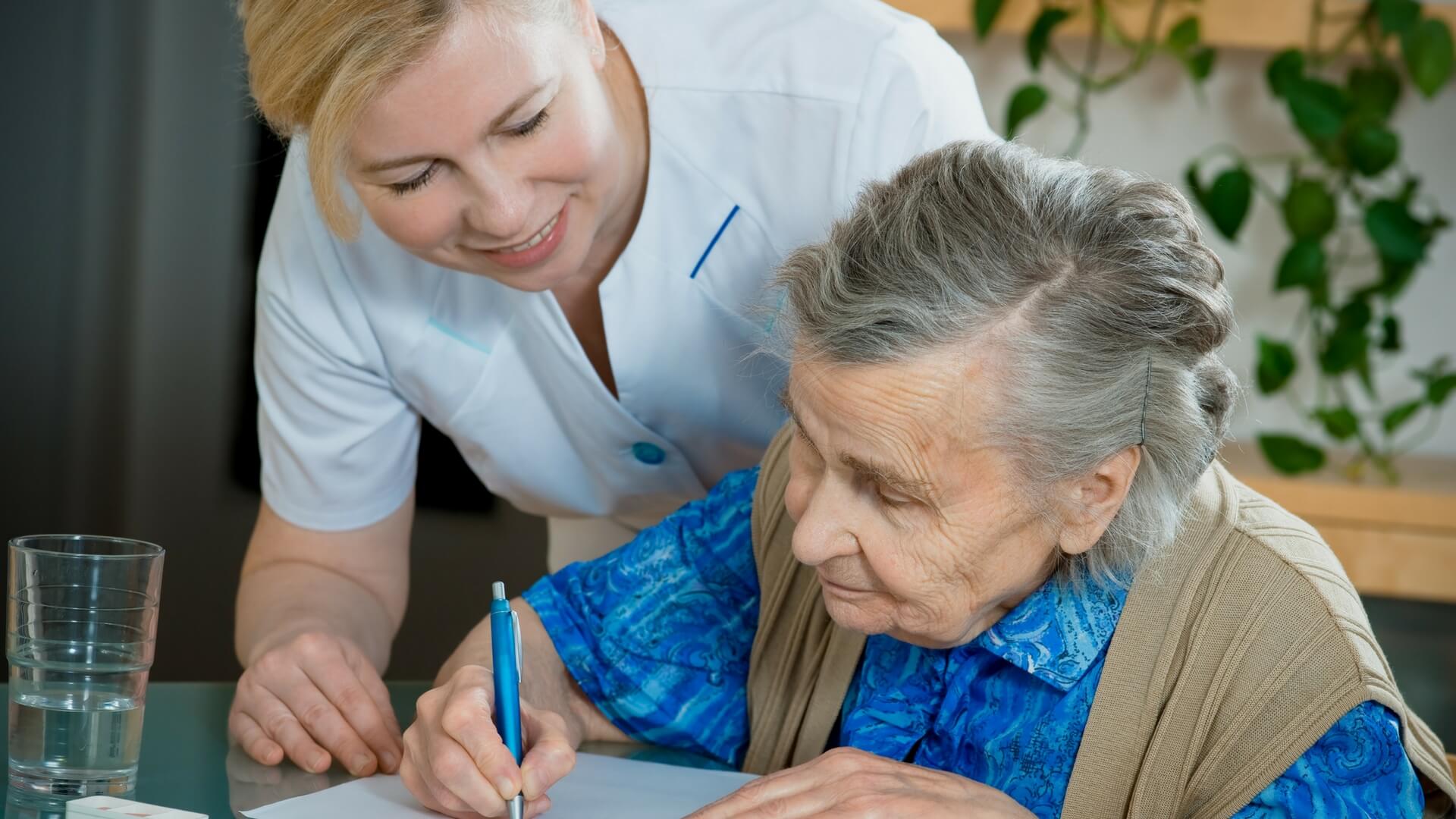 older women signing paper with nurse