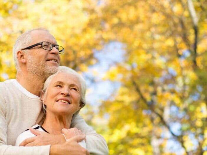 older couple hugging in front of a tree