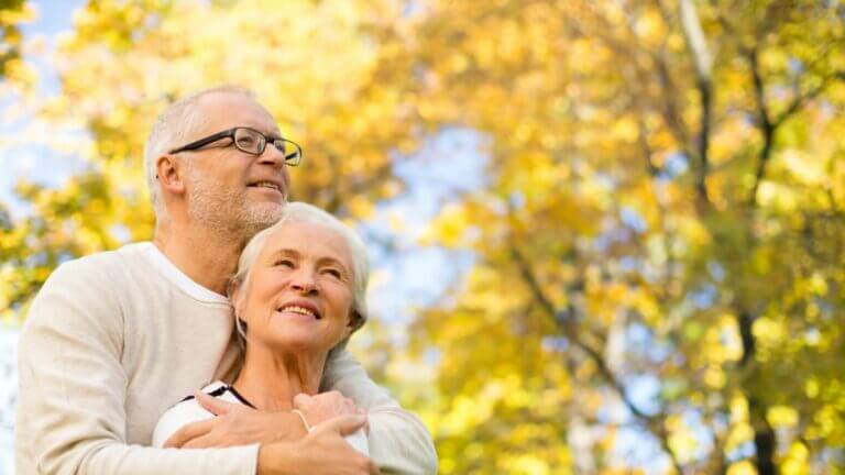 older couple hugging in front of a tree