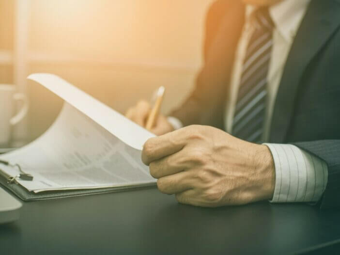 man with pencil writing on documents on a clip board