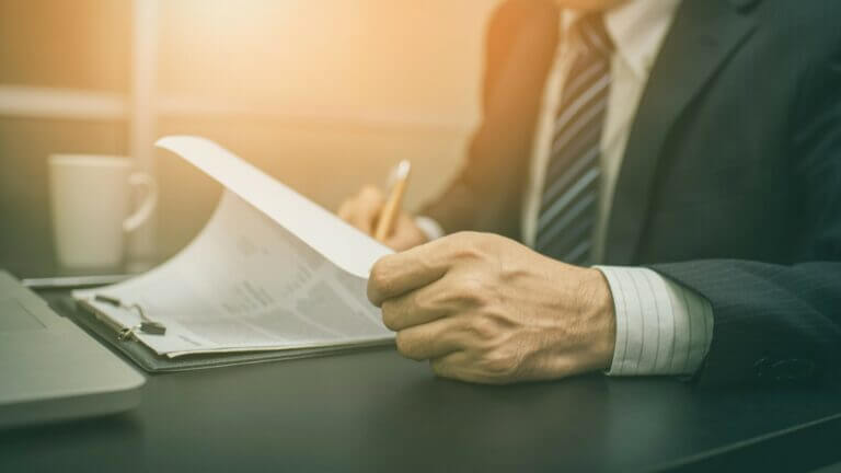 man with pencil writing on documents on a clip board