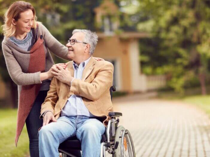 grown up daughter with father in wheelchair embracing eachother