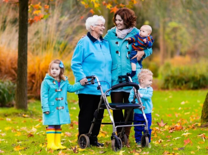mom with kids and grandma with a walker in the fall leaves