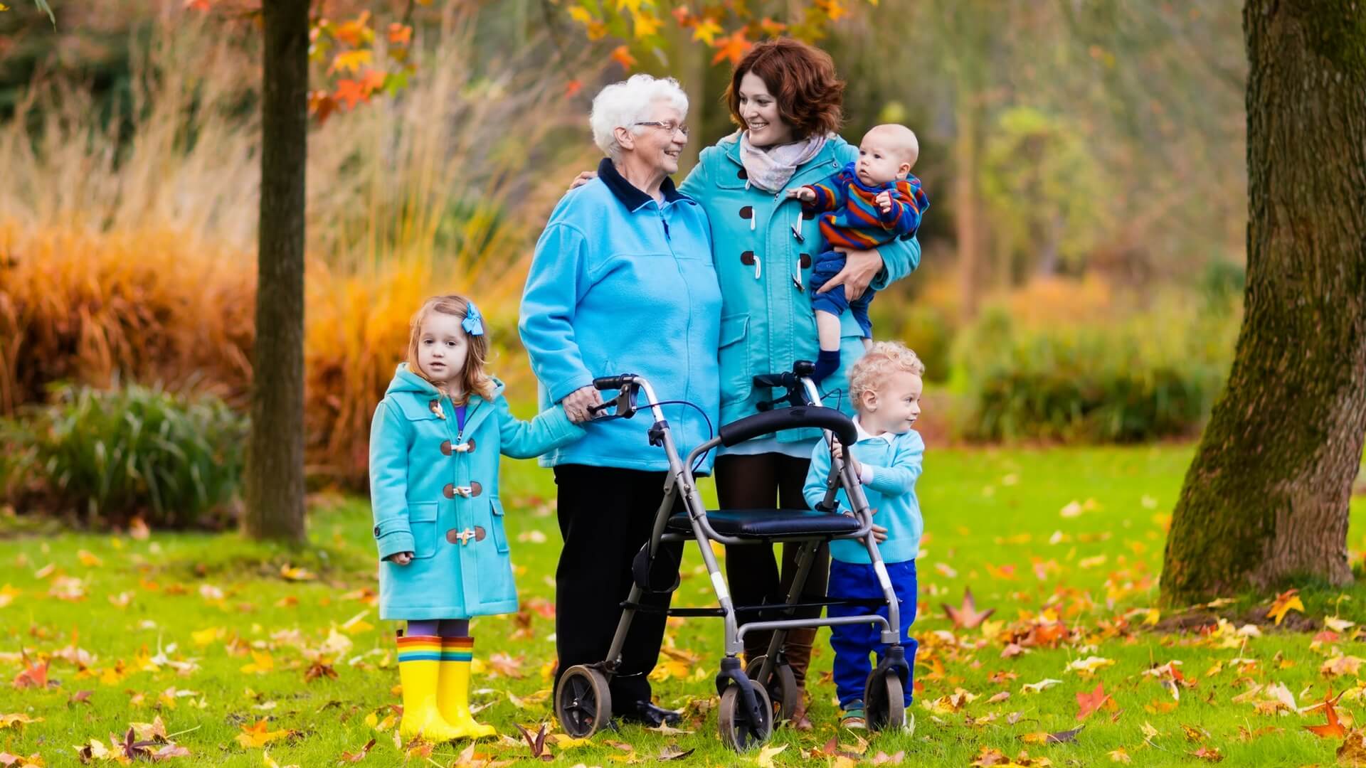 mom with kids and grandma with a walker in the fall leaves