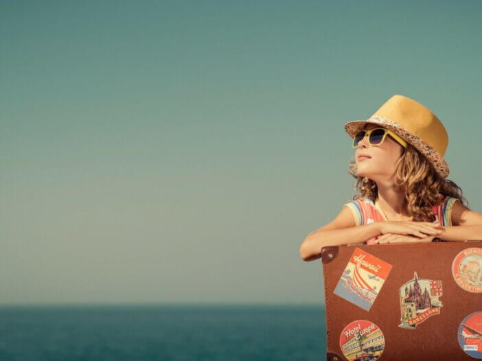 little girl with hat and glasses and travel carrier