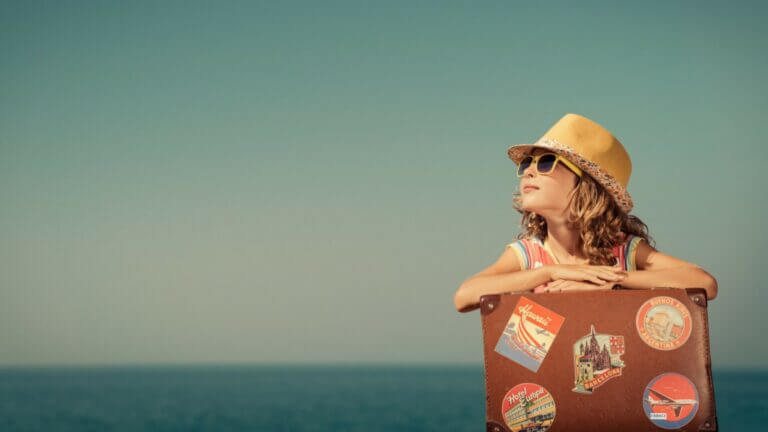 little girl with hat and glasses and travel carrier