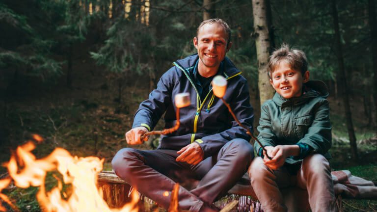 father and son at summer camp roast marshmellows