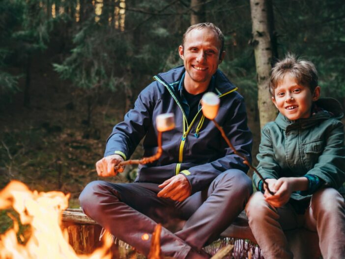 father and son at summer camp roast marshmellows
