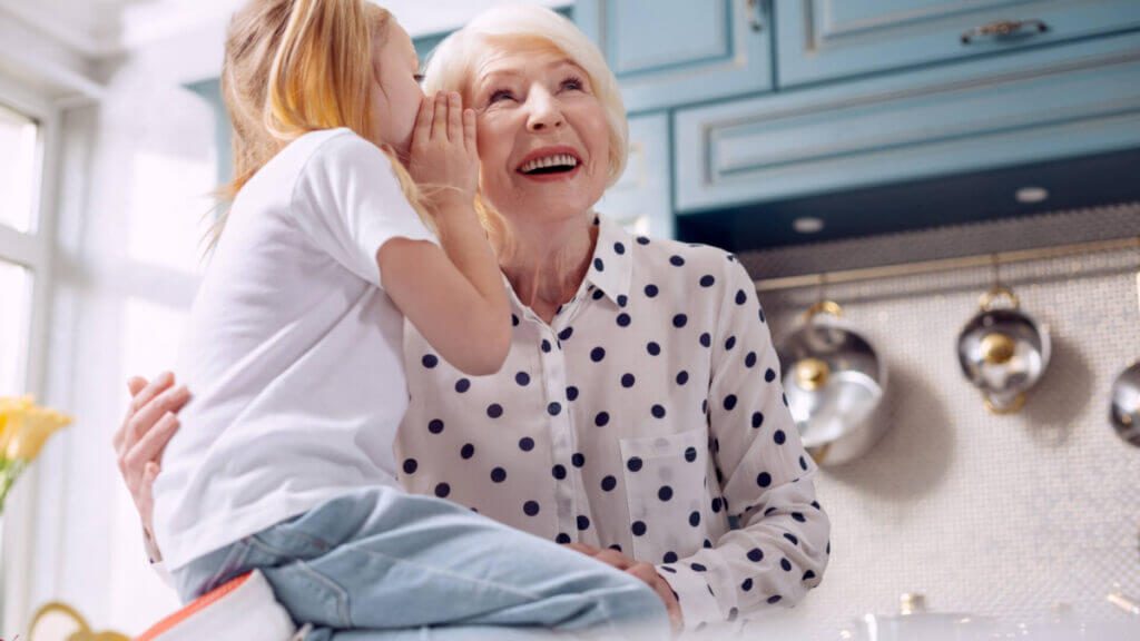 grandchild whispers in the ear of grandmother