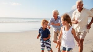 grandparents and children run on the beach
