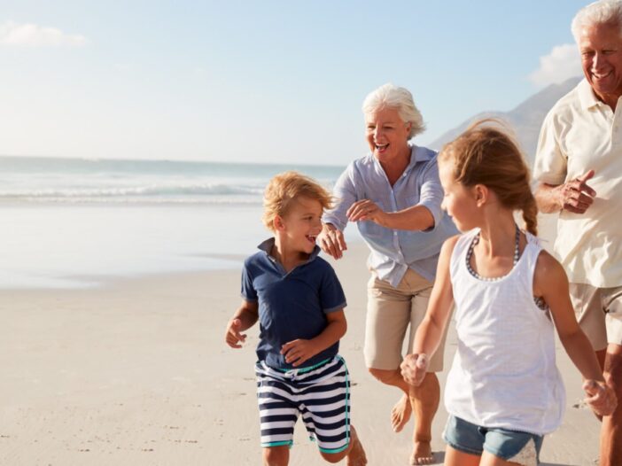 grandparents and children run on the beach