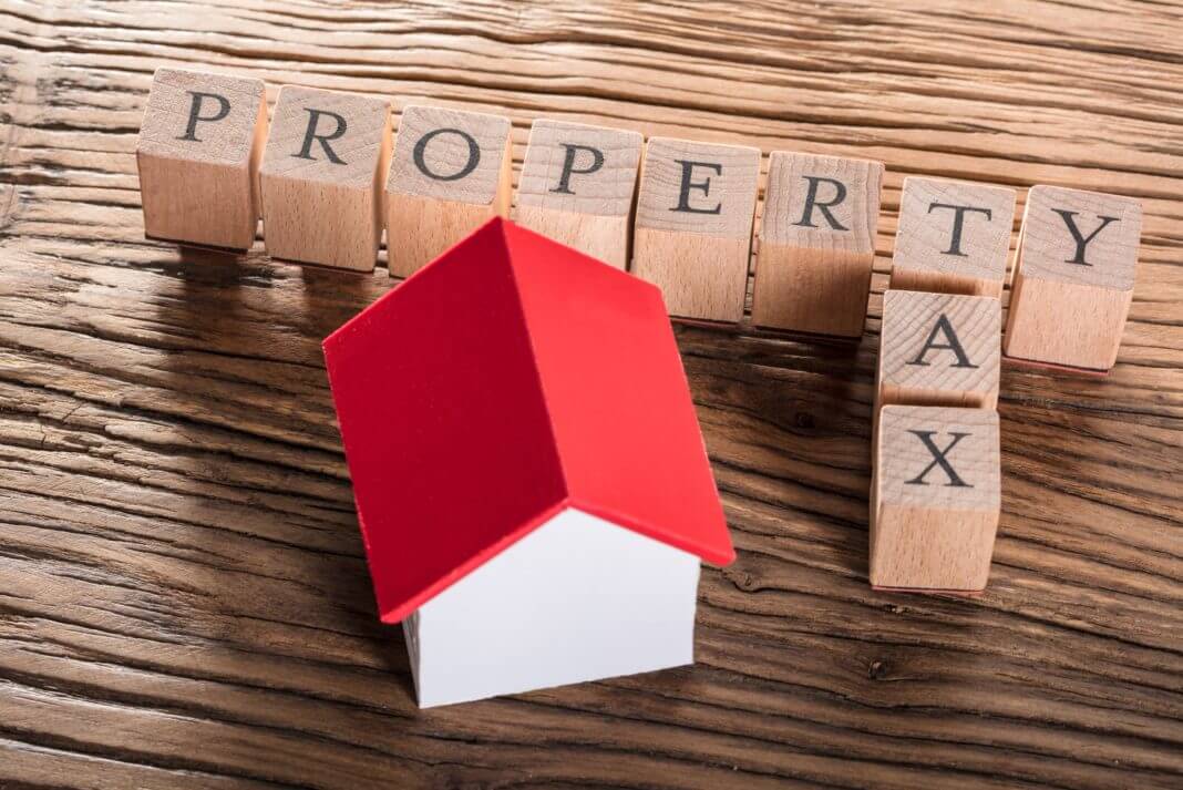 Wooden blocks spell Property Tax with small toy house