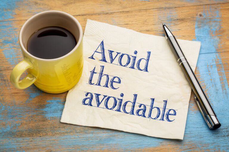Avoid the avoidable printed on a napkin next to a coffee cup and pen