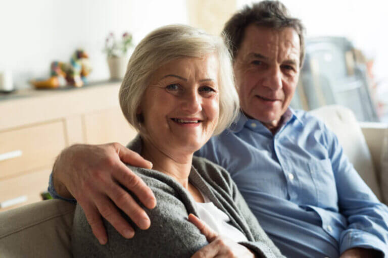 middle aged couple sitting on couch smiling