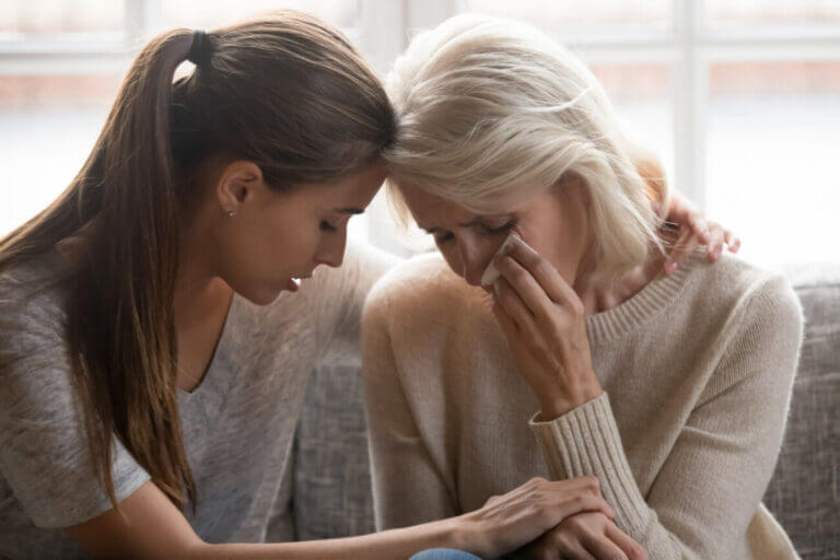 adult daughter soothes aged mother holds her hand feeling empathy