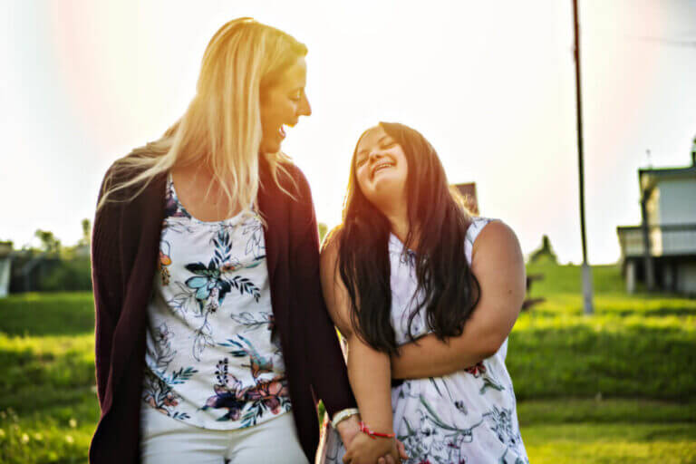 A Portrait of trisomie 21 adult girl smiling outside at sunset with family friend