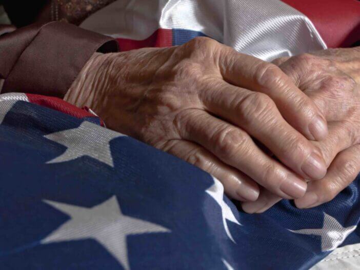 Elder person's hands holding an American flag