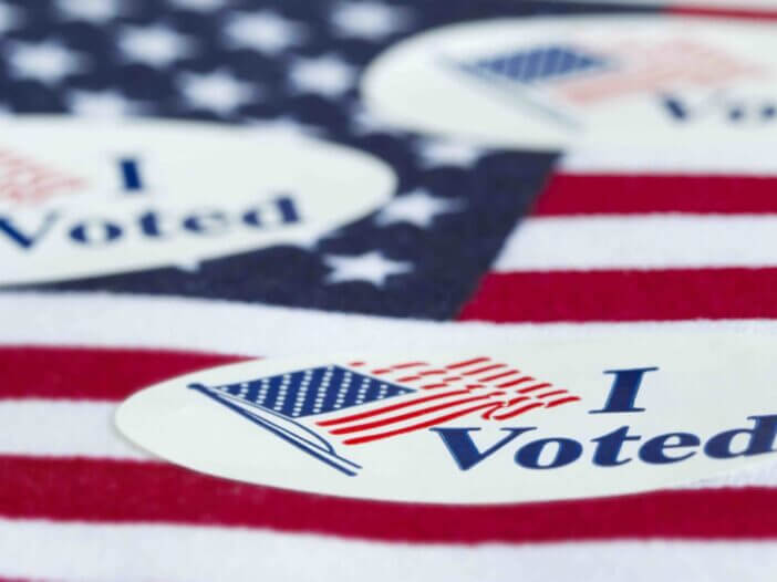 'I Voted' stickers on the US flag background.