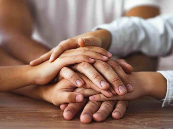 family hold hands together at the table