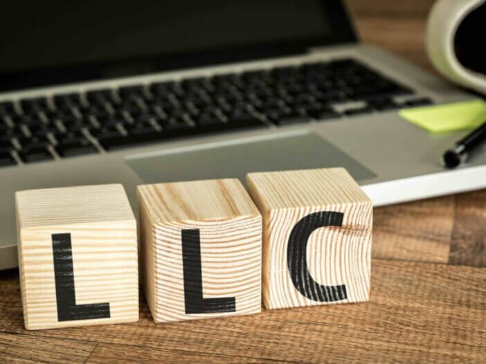 LLC (Limited Liability Company) written on a wooden cube in a office desk