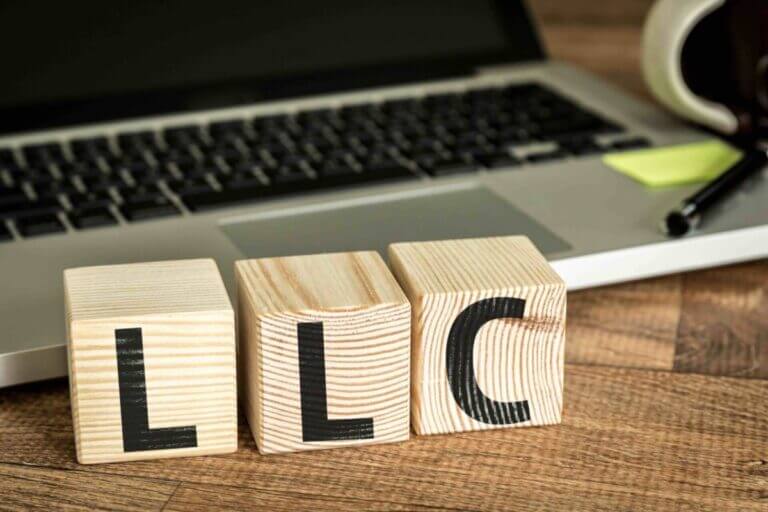 LLC (Limited Liability Company) written on a wooden cube in a office desk