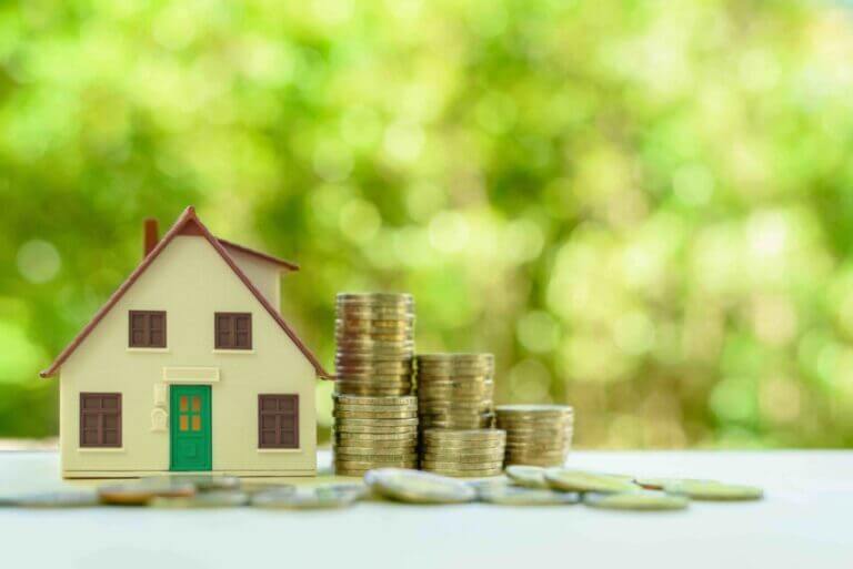 Small toy home next to stacked coins