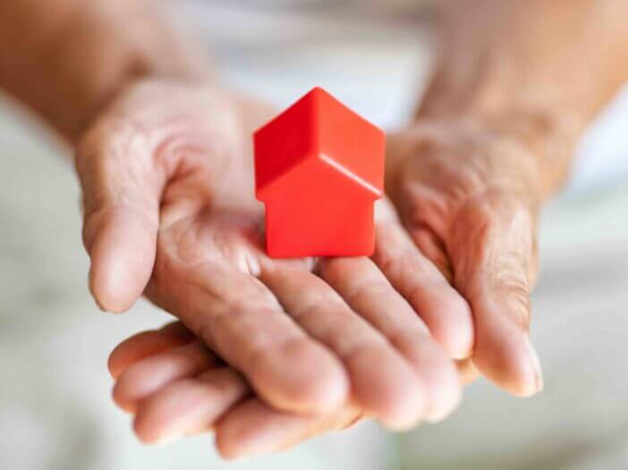 Elderly woman holding a small house in her hands